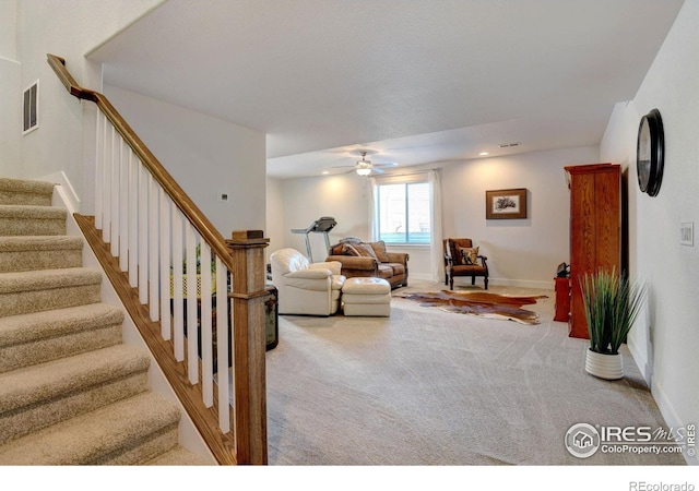 living area with a ceiling fan, visible vents, baseboards, carpet flooring, and stairs