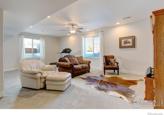 living area featuring visible vents, plenty of natural light, and light colored carpet
