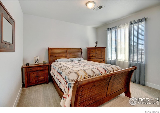 bedroom with baseboards, visible vents, and light carpet