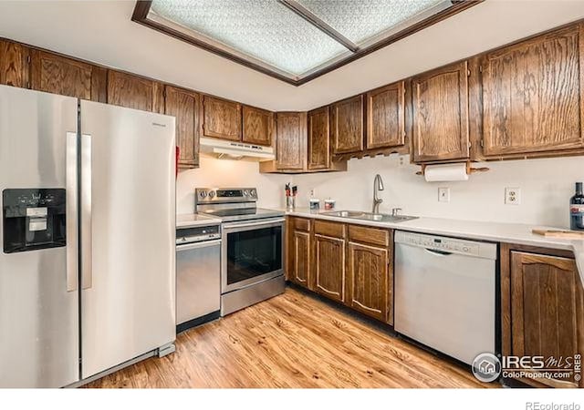 15503 E Wyoming Dr Unit G, Aurora, CO 80017 - kitchen featuring stainless steel appliances, under cabinet range hood, a sink, light countertops, and light wood-type flooring