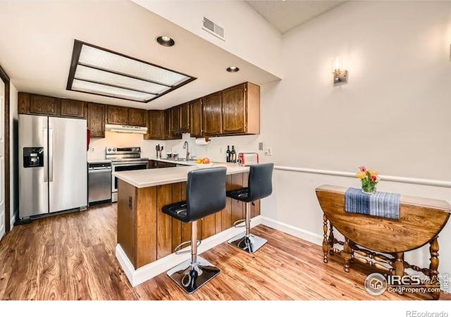 15503 E Wyoming Dr Unit G, Aurora, CO 80017 - kitchen featuring appliances with stainless steel finishes, under cabinet range hood, a peninsula, light countertops, and a sink