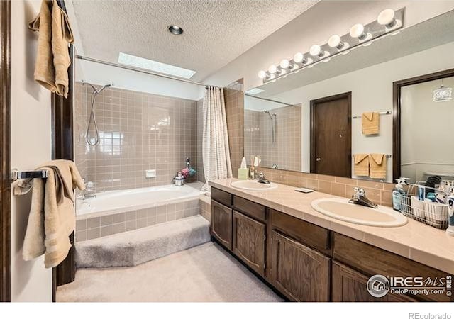 15503 E Wyoming Dr Unit G, Aurora, CO 80017 - bathroom featuring tiled shower / bath, double vanity, a textured ceiling, and decorative backsplash