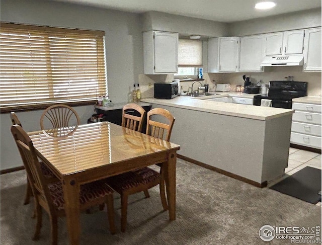 425 Stanford St, Brush, CO 80723 - kitchen featuring under cabinet range hood, range with electric stovetop, white cabinetry, a peninsula, and light countertops