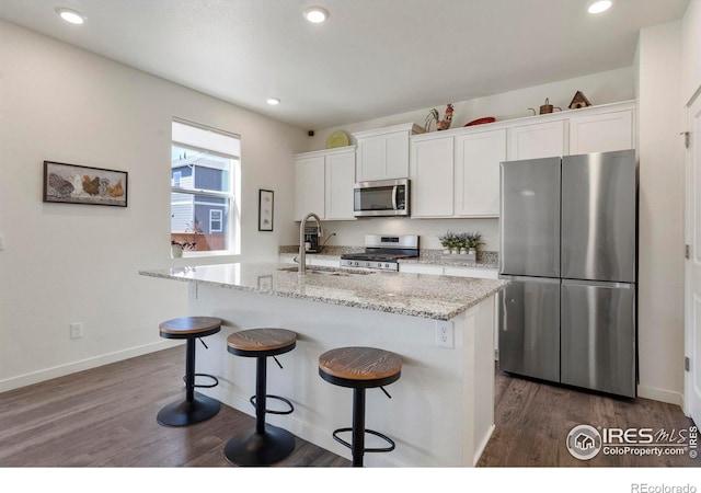 3759 Catmint St, Wellington, CO 80549 - kitchen featuring a center island with sink, a kitchen bar, white cabinets, a sink, and stainless steel appliances