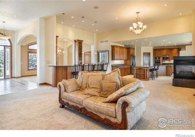 living area featuring light carpet, arched walkways, a chandelier, recessed lighting, and visible vents