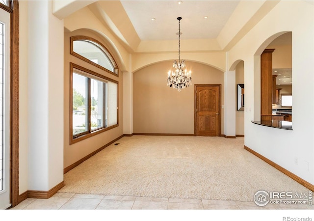 carpeted spare room featuring arched walkways, tile patterned floors, a chandelier, recessed lighting, and baseboards