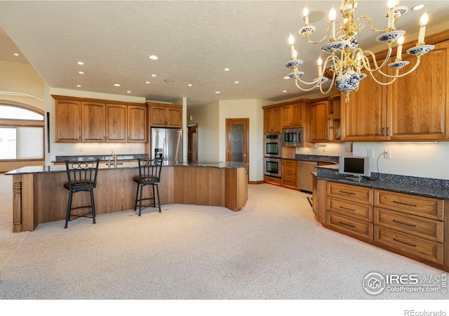 kitchen with brown cabinetry, an inviting chandelier, recessed lighting, light colored carpet, and appliances with stainless steel finishes