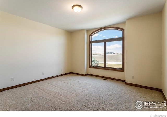 carpeted empty room with baseboards