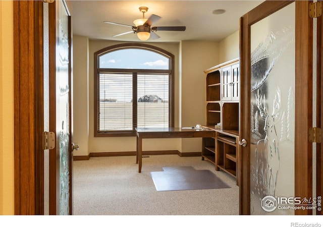 unfurnished office featuring baseboards, ceiling fan, and carpet