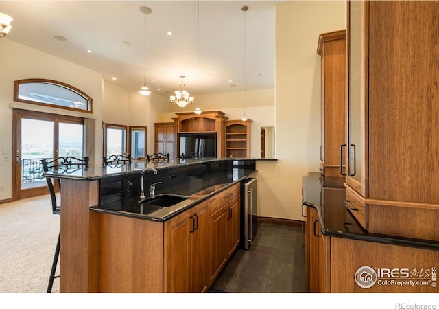 kitchen featuring a kitchen breakfast bar, brown cabinetry, a sink, baseboards, and an inviting chandelier