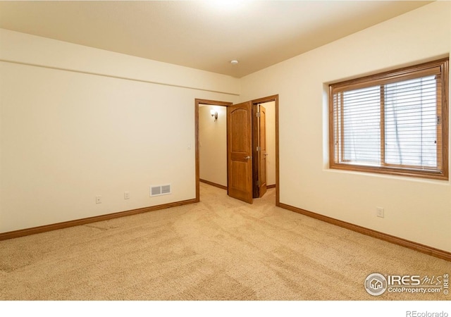 empty room with visible vents, baseboards, and light colored carpet
