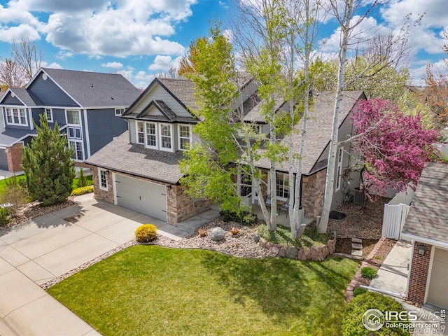 109 Whitney Ct, Windsor, CO 80550 - craftsman-style home featuring driveway, stone siding, a garage, a front lawn, and roof with shingles