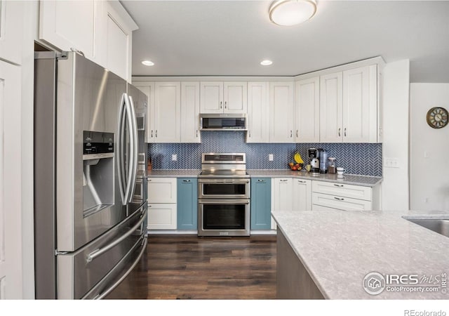 109 Whitney Ct, Windsor, CO 80550 - kitchen with appliances with stainless steel finishes, light countertops, dark wood finished floors, white cabinets, and backsplash