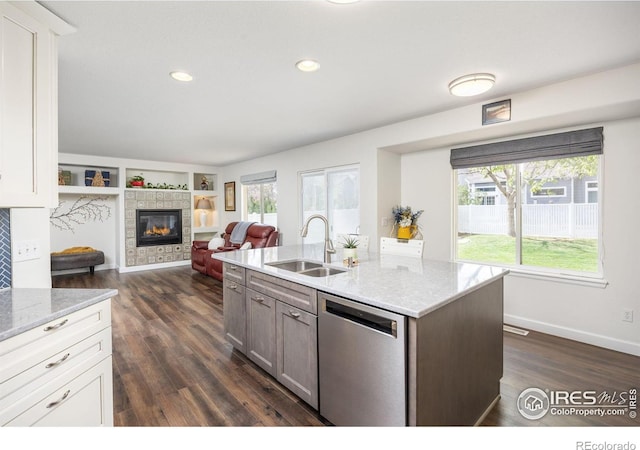 109 Whitney Ct, Windsor, CO 80550 - kitchen featuring a sink, dishwasher, dark wood-style floors, a tiled fireplace, and light stone counters
