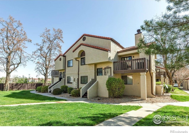 5035 W 73rd Ave, Westminster, CO 80030 - view of front of home with a chimney, a balcony, fence, stucco siding, and a front lawn