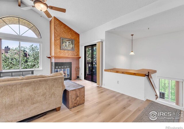 5035 W 73rd Ave, Westminster, CO 80030 - living area with wood finished floors, a textured ceiling, high vaulted ceiling, a fireplace, and a ceiling fan
