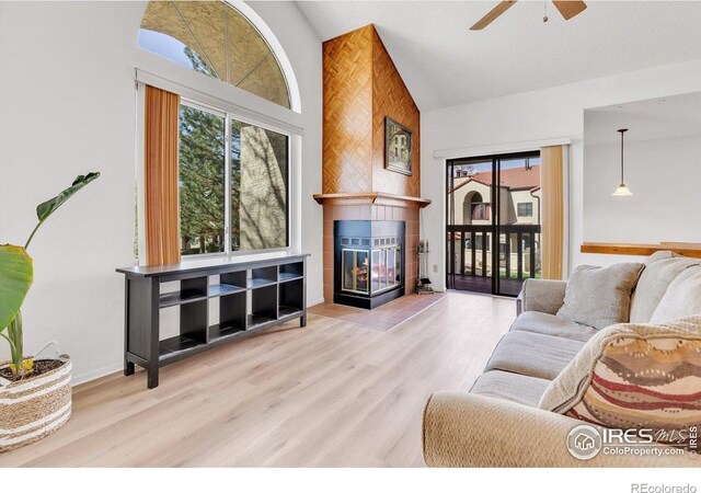 5035 W 73rd Ave, Westminster, CO 80030 - living room featuring ceiling fan, a tiled fireplace, a healthy amount of sunlight, and high vaulted ceiling