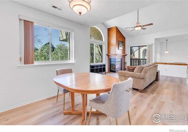5035 W 73rd Ave, Westminster, CO 80030 - dining space with lofted ceiling, visible vents, a fireplace, ceiling fan, and light wood-style floors