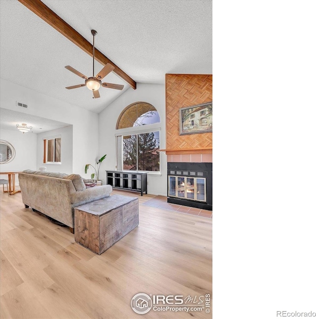 5035 W 73rd Ave, Westminster, CO 80030 - living room with a tile fireplace, ceiling fan, visible vents, wood finished floors, and lofted ceiling with beams