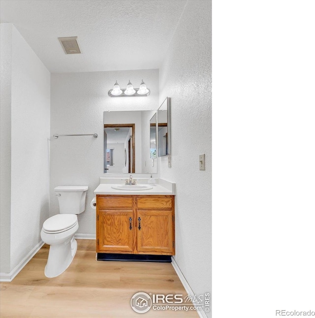 5035 W 73rd Ave, Westminster, CO 80030 - bathroom with toilet, wood finished floors, visible vents, a textured wall, and vanity