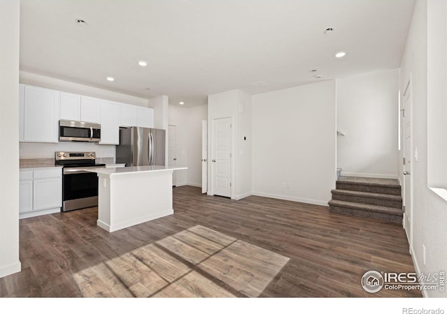 kitchen with white cabinetry, stainless steel appliances, dark wood-style floors, and a kitchen island