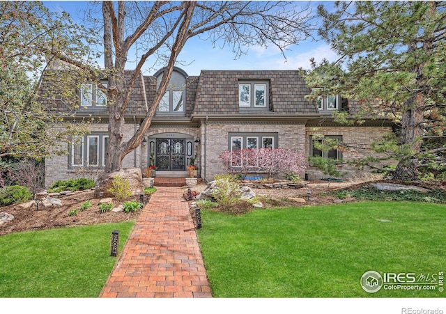 view of front of home with brick siding, mansard roof, french doors, and a front lawn
