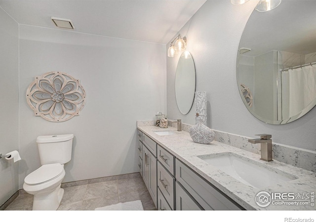 bathroom with a sink, baseboards, toilet, and double vanity