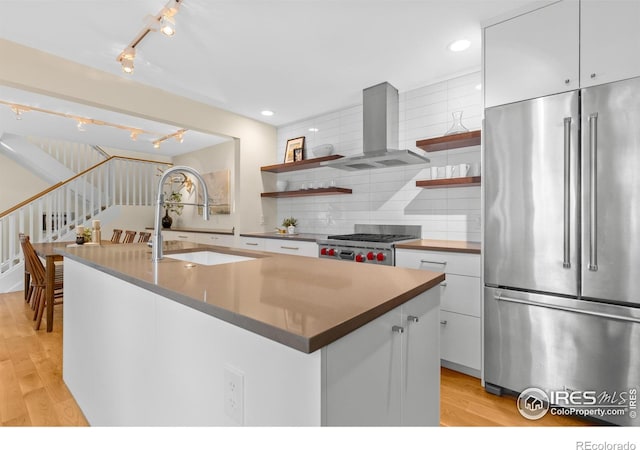kitchen featuring open shelves, rail lighting, wall chimney range hood, and high quality fridge
