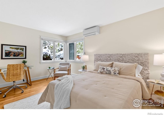 bedroom with baseboards, wood finished floors, and a wall mounted air conditioner