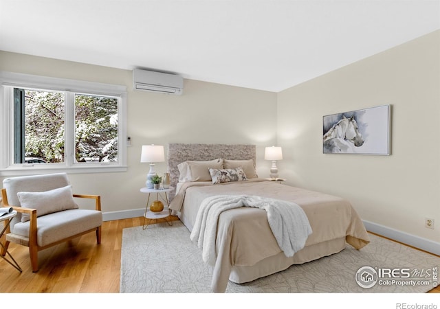 bedroom featuring an AC wall unit, baseboards, and wood finished floors