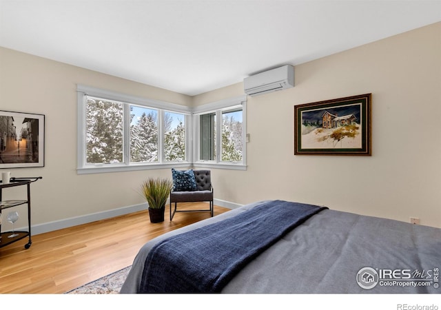 bedroom with baseboards, a wall mounted AC, and wood finished floors
