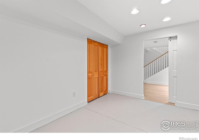 empty room with recessed lighting, baseboards, stairs, and concrete floors