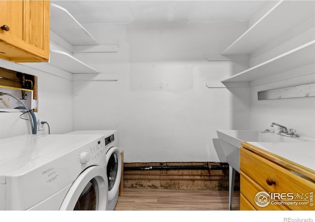 laundry area featuring washing machine and dryer, light wood-type flooring, and cabinet space