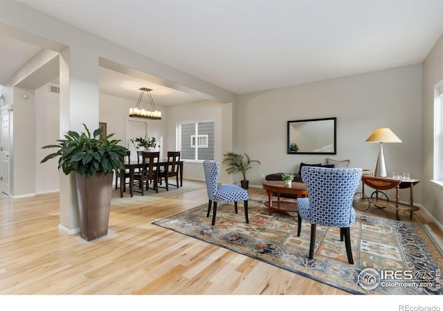 living area with baseboards, wood finished floors, a chandelier, and visible vents