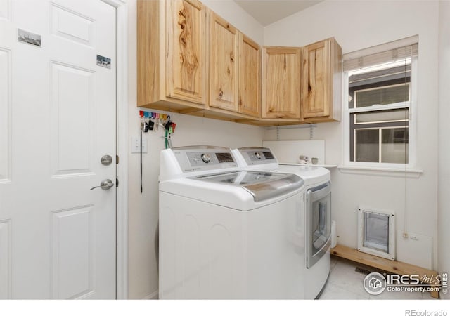 laundry room with cabinet space, light tile patterned floors, and washing machine and dryer