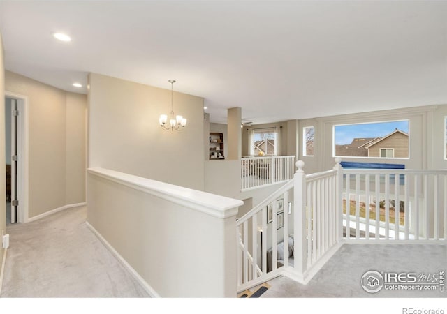 hall featuring carpet flooring, a notable chandelier, recessed lighting, baseboards, and an upstairs landing