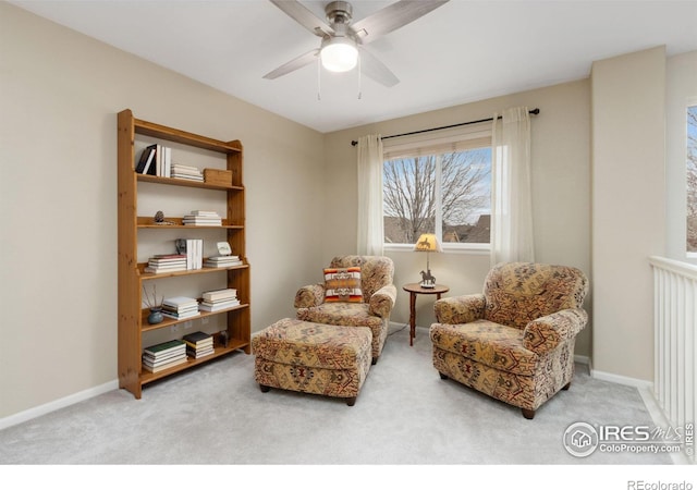 living area featuring baseboards, a ceiling fan, and carpet flooring