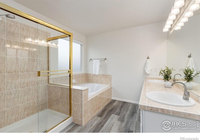 full bath with a sink, double vanity, wood finished floors, a bath, and a stall shower