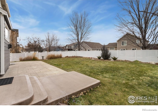 view of yard with a fenced backyard, a patio, and a residential view
