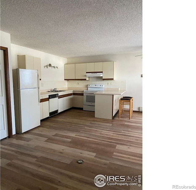 1961 Centennial Dr, Louisville, CO 80027 - kitchen featuring white appliances, under cabinet range hood, a peninsula, light countertops, and backsplash