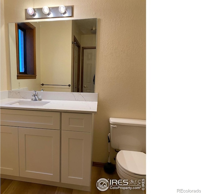 1961 Centennial Dr, Louisville, CO 80027 - bathroom with toilet, vanity, a textured wall, and wood finished floors