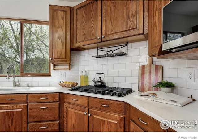 4866 Franklin Dr, Boulder, CO 80301 - kitchen with decorative backsplash, brown cabinetry, a sink, stainless steel microwave, and black gas stovetop