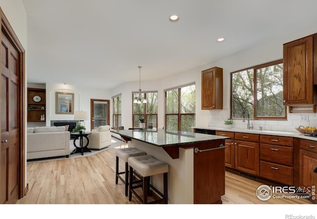 4866 Franklin Dr, Boulder, CO 80301 - kitchen with decorative backsplash, a kitchen breakfast bar, brown cabinetry, a sink, and light wood finished floors