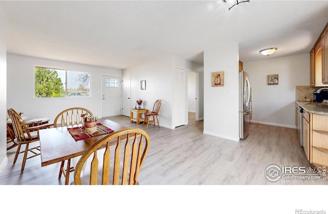 dining space with baseboards and light wood-style floors