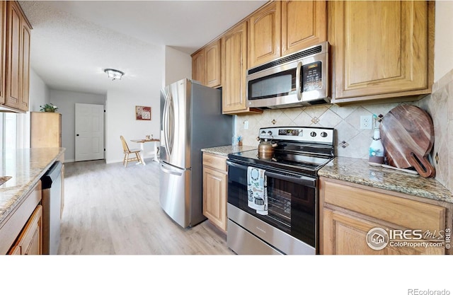 kitchen featuring backsplash, light wood-type flooring, light stone counters, baseboards, and stainless steel appliances