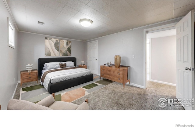 carpeted bedroom featuring crown molding, baseboards, and visible vents