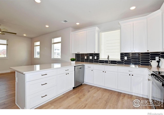 kitchen featuring stainless steel dishwasher, a sink, a peninsula, black electric range oven, and light wood-type flooring