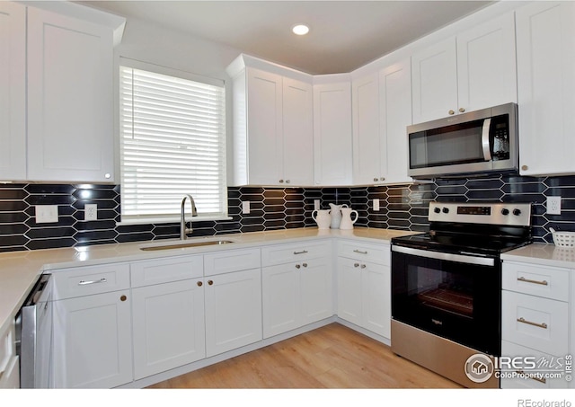 kitchen featuring stainless steel appliances, a sink, white cabinetry, light countertops, and recessed lighting