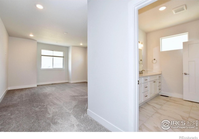 hall with recessed lighting, a sink, baseboards, light marble finish flooring, and light carpet