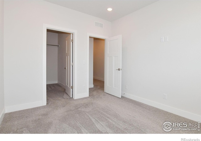 unfurnished bedroom with carpet flooring, a walk in closet, baseboards, and recessed lighting